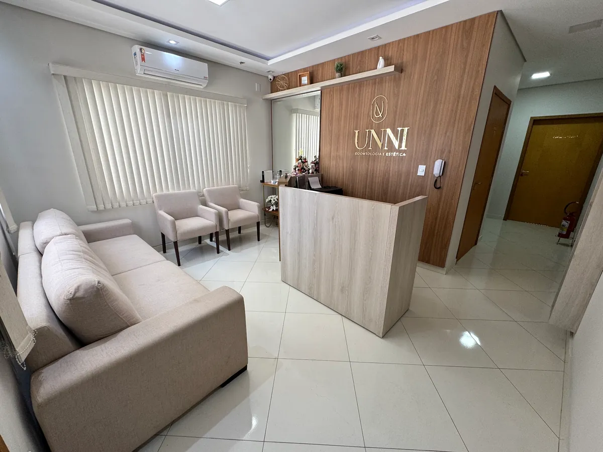 Recepção da UNNI com painel de madeira, logo dourada e sofá